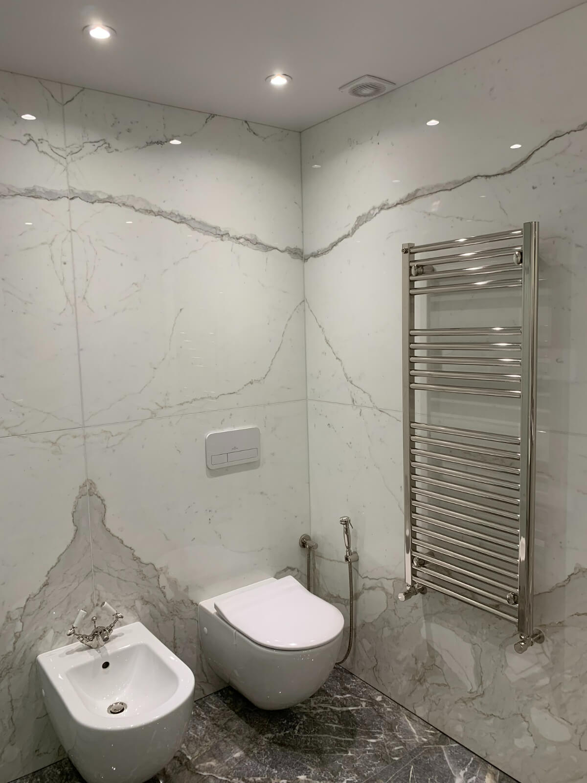 A bathroom with white marble walls and a toilet.