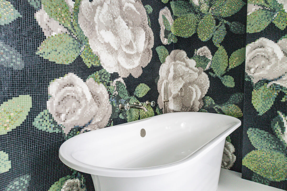 A white bathtub in a bathroom with a black and white floral wallpaper.